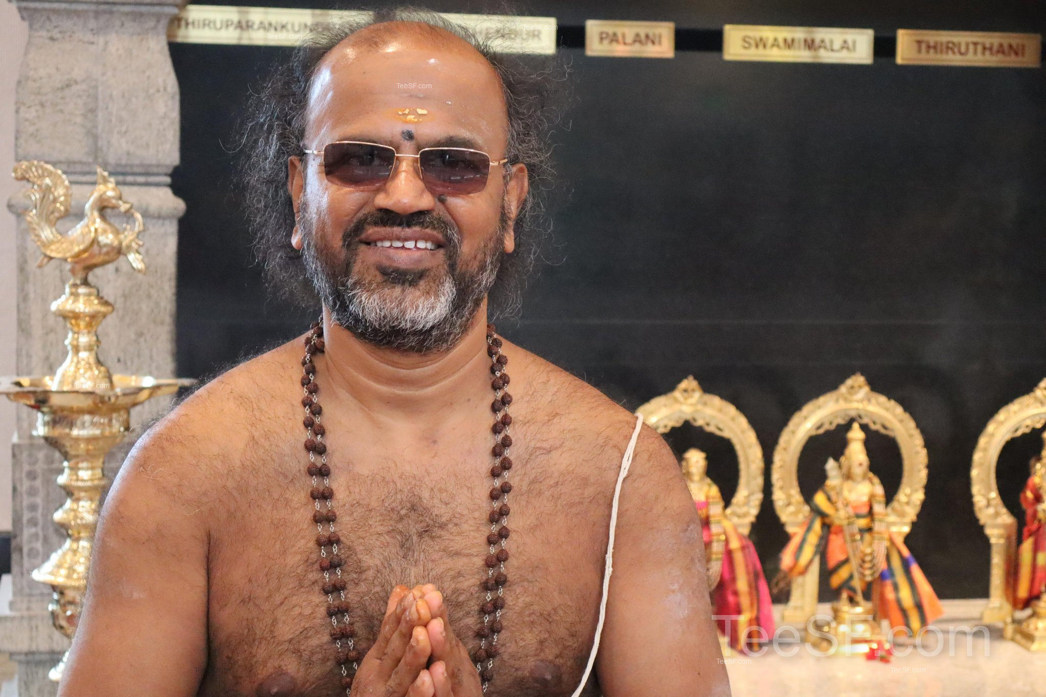 A warm portrait inside Shiva Murugan Temple with shrine figures in the background.